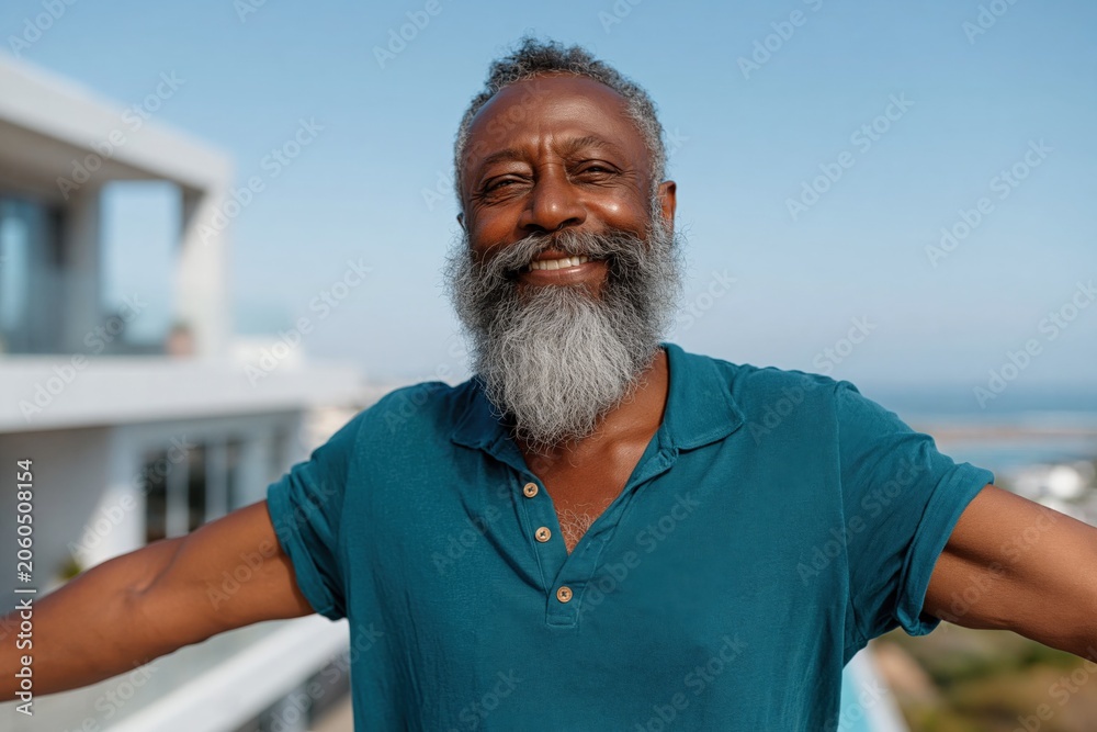 Obraz premium Elderly man with long gray beard embracing ocean view balcony