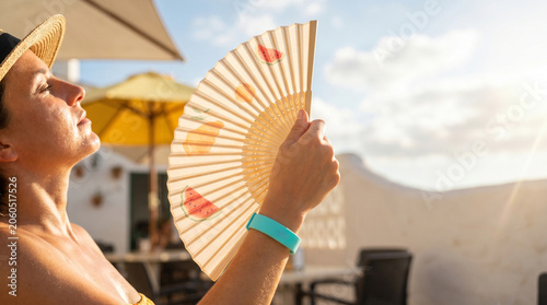 Woman enjoying sunshine while holding a hand fan outdoors  