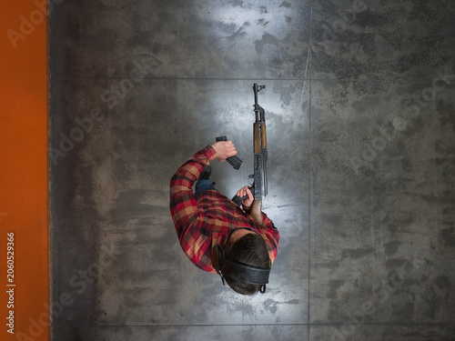 Εκτύπωση καμβά Top Down View of Man in Flannel Shirt Reloading Classic Soviet Assault Rifle Cha
