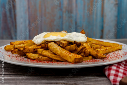 French fries with fried egg and paprika on plate