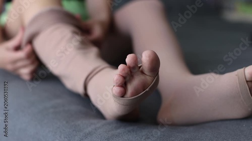 Woman seating on a bed takes compression stockings off. 4K
