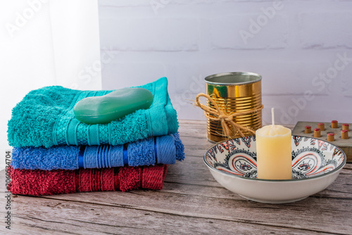 A stack of colorful towels, a bar of soap, and a candle.
