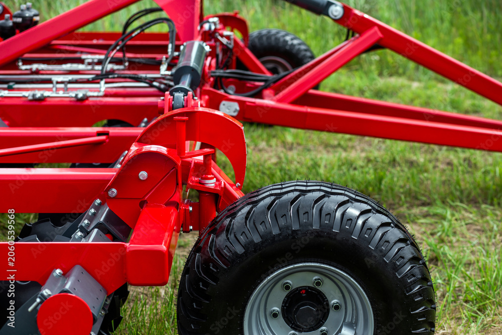 Obraz premium Red agricultural machine stands in green grass