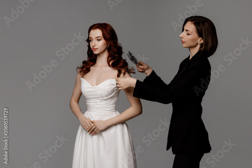 Φωτογραφία Elegant studio scene with a woman in a white strapless dress seated while a styl
