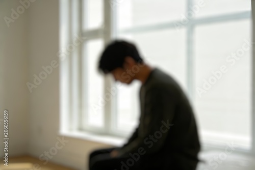 Defocused male silhouette indoors representing sadness, anxiety, loneliness, and mental health awareness.
