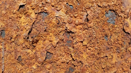 Close-up texture of heavily rusted metal surface with peeling paint and corrosion showing orange and brown tones