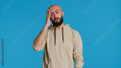 Foto Muslim man suffering from serious migraine on camera, trying to rub temples to ease the pressure