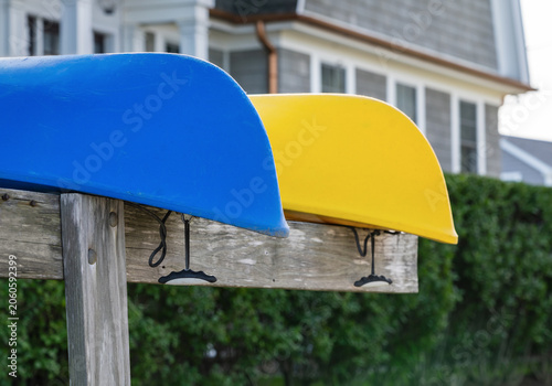 Close up view of bright blue and yellow kayaks on a boat rack by the beach in coastal Connecticut.