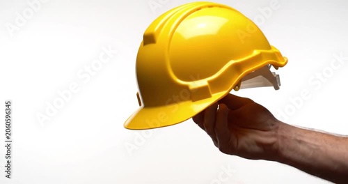 Hands holding a yellow hard hat on a white background, protective construction safety gear for industrial work environment.