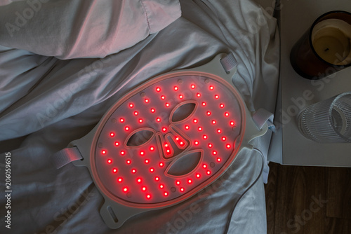 Red light therapy face mask on bed at home