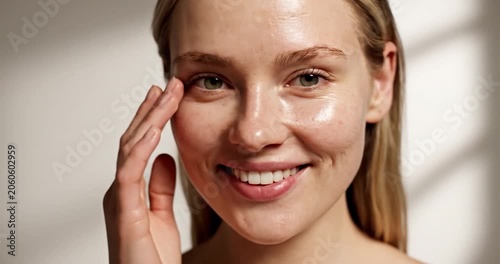 Smiling woman with natural skin texture touching her face for skincare