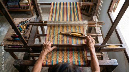 Local Flavor Top view of artisan hands weaving colorful traditional silk fabric on a wooden loom with a shuttle