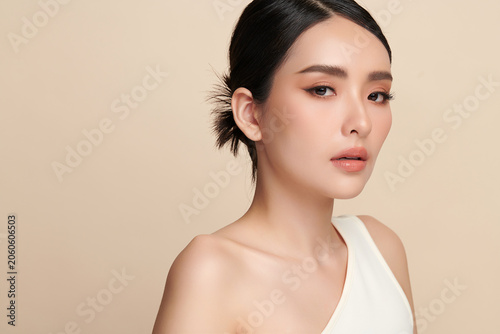 Photography A beautiful young Asian woman with clean, fresh skin against a beige background