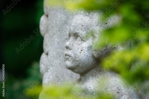 Photos A detailed close-up of a weathered stone child sculpture on a historic tomb at M