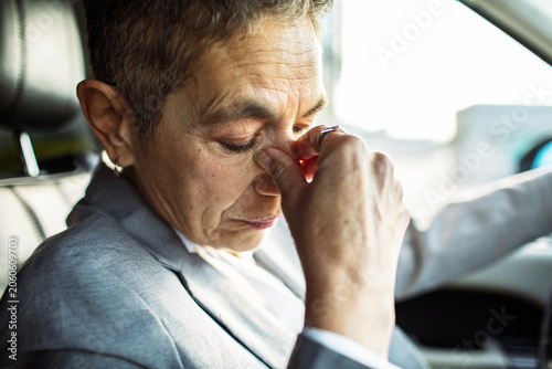 Stressed adult driver rubbing eyes in car