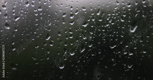 Raindrops are running down the window glass. Bad weather outside. Rain storm and thunderstorm outside the window.