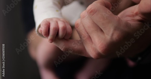 The small palm of a newborn baby embraces the finger of an adult. The baby's small fingers.