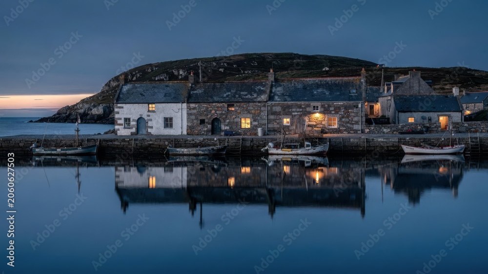 Fototapeta premium Tranquil fishing harbour village at blue hour with reflections and moored boats