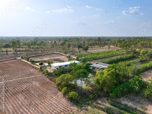 Cuadro en lienzo Aerial view of sustainable rural farm with solar powered infrastructure, agricultural fields, water pond and tropical landscape under clear sky, showcasing renewable energy and self sufficient living