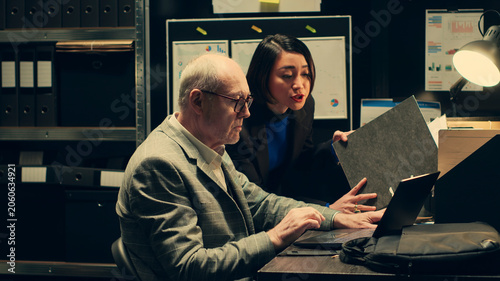 Photos Private detectives reviewing forensic evidence folders in police archive room, collaborating on creating a profile for culprit