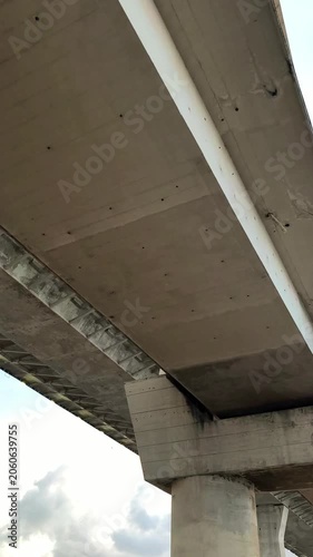 Low-angle view of a modern concrete Pumarejo bridge with steel beams and support pillars silhouetted against a soft sunset sky with clouds, creating an urban infrastructure background.