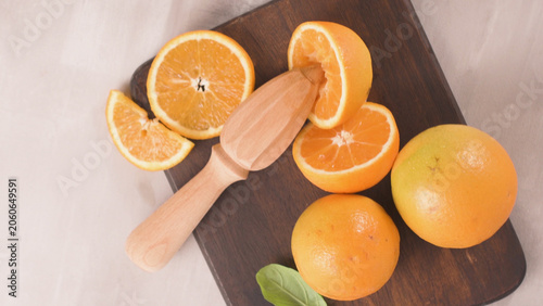 фотографія Fresh oranges on a cutting board being juiced with a wooden reamer
