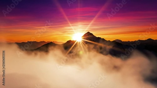 Serene mountain peak above clouds at sunrise with vibrant purple, orange, and yellow hues