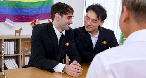 фотографія Gay male couple from the LGBTQ community achieved their dream legally recognized equal marriage happily signing their marriage registration documents office in front registrar witnessed love