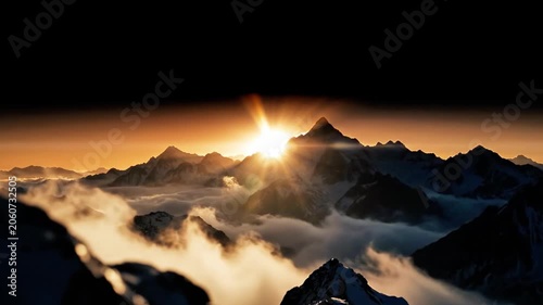 A breathtaking mountain range at sunrise with the sun peeking through peaks above clouds