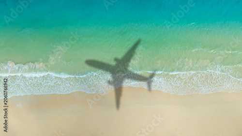 Aerial view of shadow passenger plane silhouette and sandy beach blue sea with waves at sea beach summer vacation sea travel concept	
