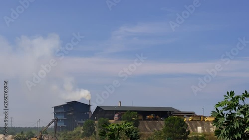 Palm Oil Processing Plant with Smoke Emissions Under Blue Sky