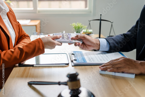 Obraz na plátně Close view of a cash payment exchanged across a lawyer’s desk with legal papers, gavel and scales in the background, suggesting bribery, corruption or an illegal business deal
