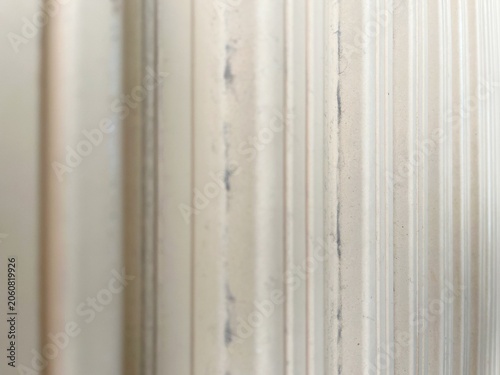 Vertical lines of beige corrugated metal with selective focus and blur. 