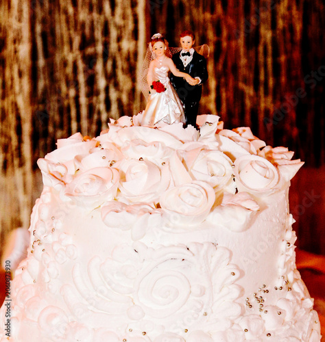 White cake topped with wedding couple figurines