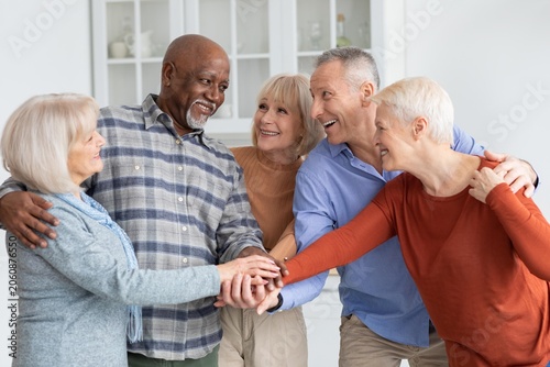 Εκτύπωση καμβά Joyful Multiracial Group Of Four Adults, Two Males And Two Females, Smiling And Holding Hands While Sharing A Moment Of Happiness At Home