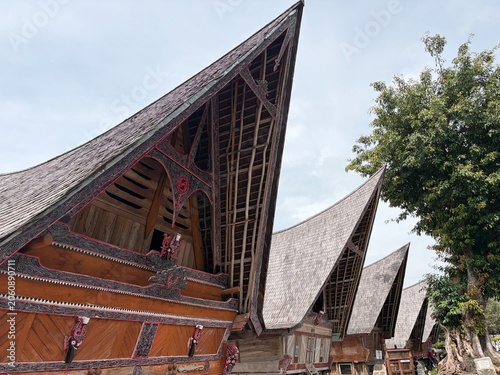 Traditional Batak Toba traditional house (Rumah Bolon) with its iconic boat-shaped roof and intricate Gorga carvings in Samosir Island, Lake Toba, Indonesia