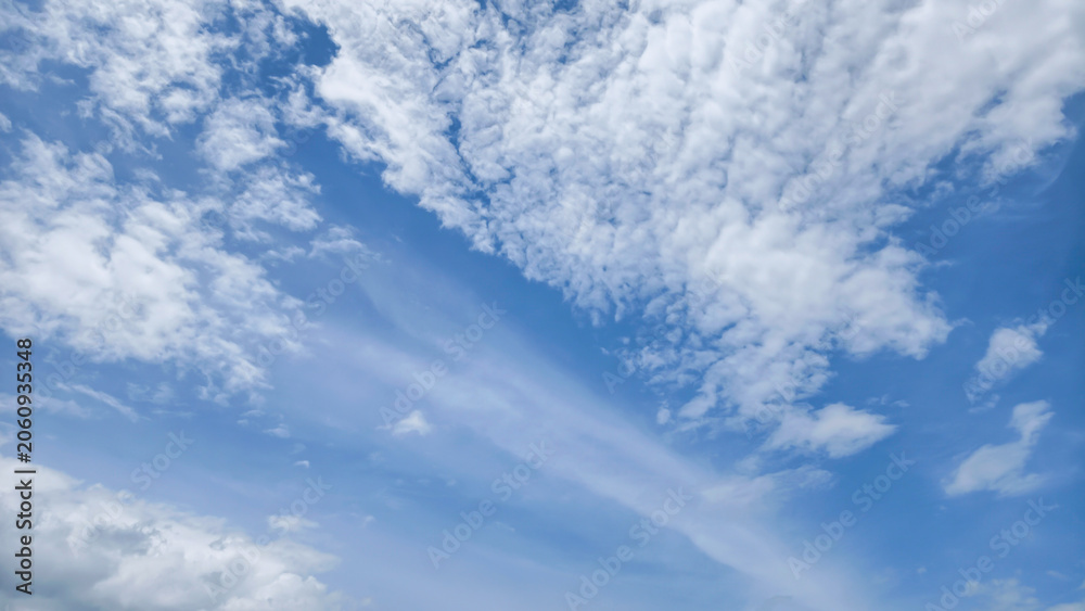 Fototapeta premium Wispy White Clouds Drifting Across A Clear Bright Blue Sky On A Beautiful Sunny Summer Day