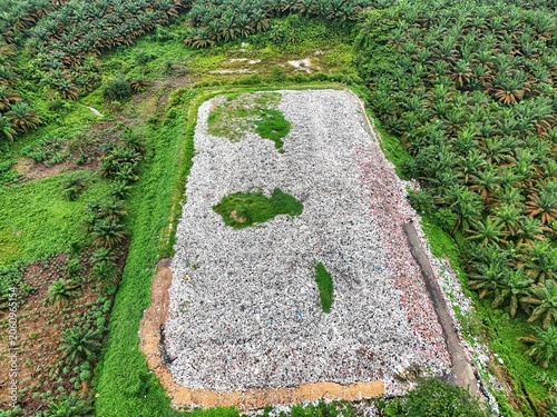 Aerial view of a large pile of waste in a clearing surrounded by palm trees.