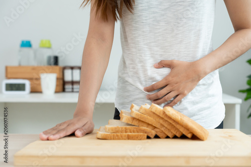 Fotografie Wheat allergy, gluten allergy, women reactions stomachache eating eat bread, swo