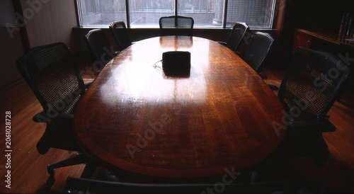 Dimly lit boardroom with polished oval table and chairs