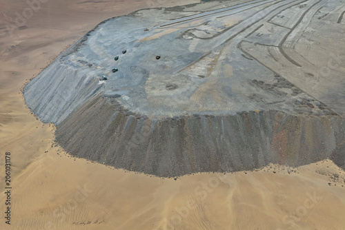 Huge mine embankment slope and desert platform with machinery, drone view