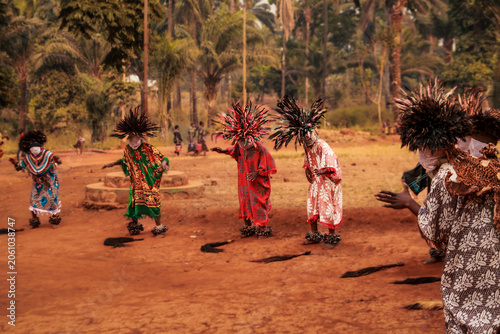 Billede på lærred Masked dancers, wearing woven face coverings, colorful robes, and elaborate feathered headdresses,  perform a traditional ceremonial dance in the Babungo Kingdom of Cameroon