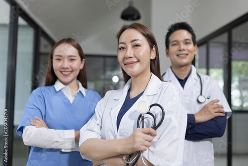 Portrait of a confident team of Asian doctors and medical staff smiling and standing together in a modern hospital corridor.