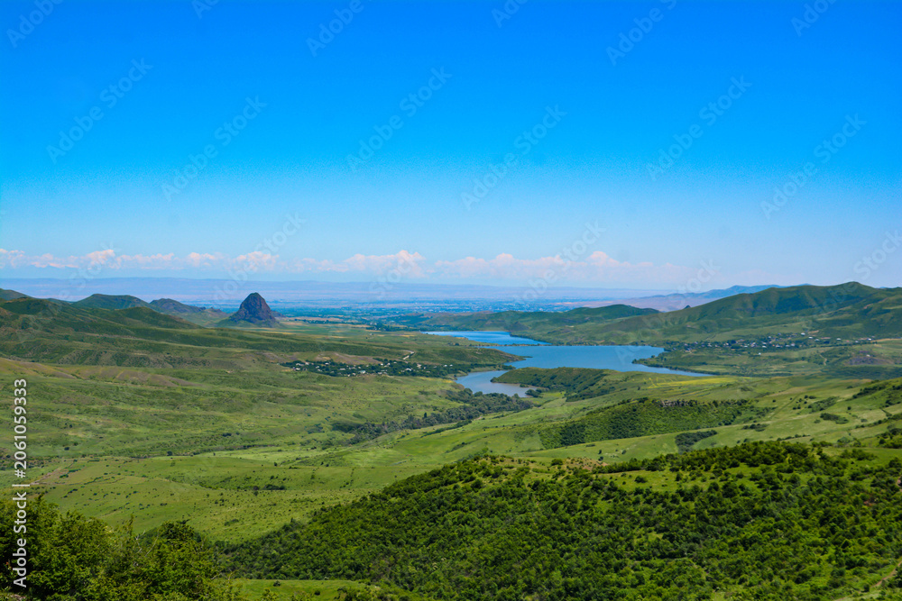 Fototapeta premium View of the mountain and the valley. The landscape of the lake with mountains in the background. Beautiful nature landscape with lake, green fields and mountains. River and mount