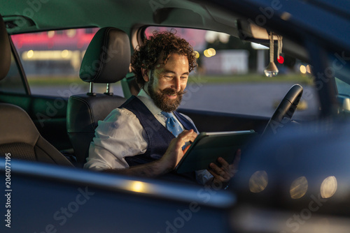 Obraz na płótnie Professional man working remote with tablet inside car