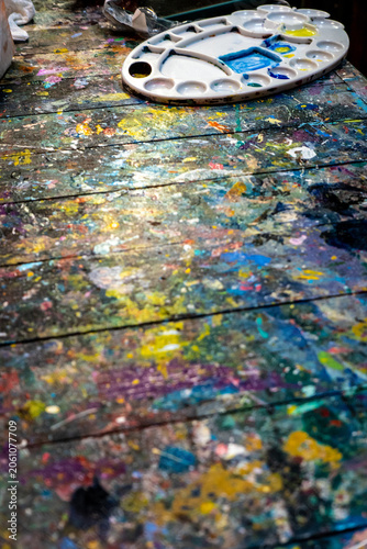 Paint stains have accumulated on the wooden table in the art studio