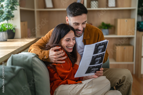 Tablou pe pânză Happy couple looking at ultrasound images anticipating future parenthood