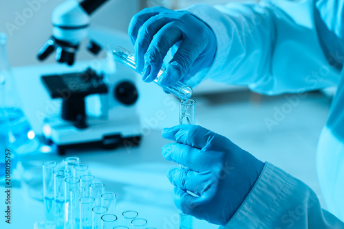 Scientist hands in blue glo...