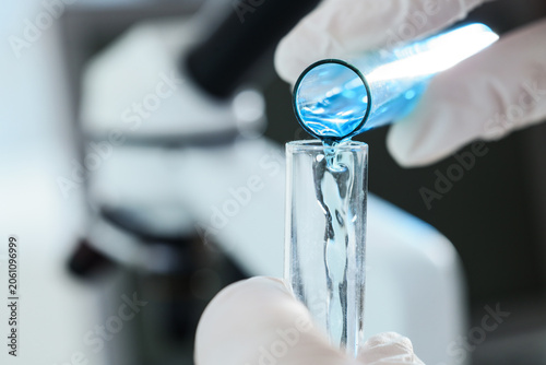 Scientific research and development with blue liquid pouring into test tube i...