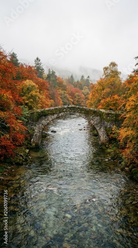 Autumn Stone Bridge Over Stream in Misty Forest with Vibrant Fall Foliage